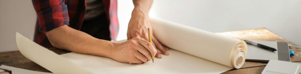 Male contractor drawing draft on paper roll